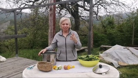 Vittoria all'aperto dietro un tavolo con pentola, cesto intrecciato, ciotola di erbe fresche e fiori di calendula