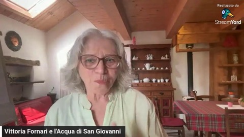 Vittoria in camicia verde chiaro parla nella cucina di casa, tra travi di legno, lucernario e la credenza con le ceramiche